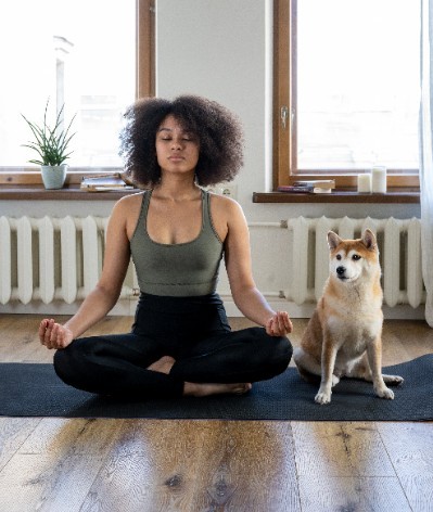 Working out from home - woman stretching with dog on yoga mat